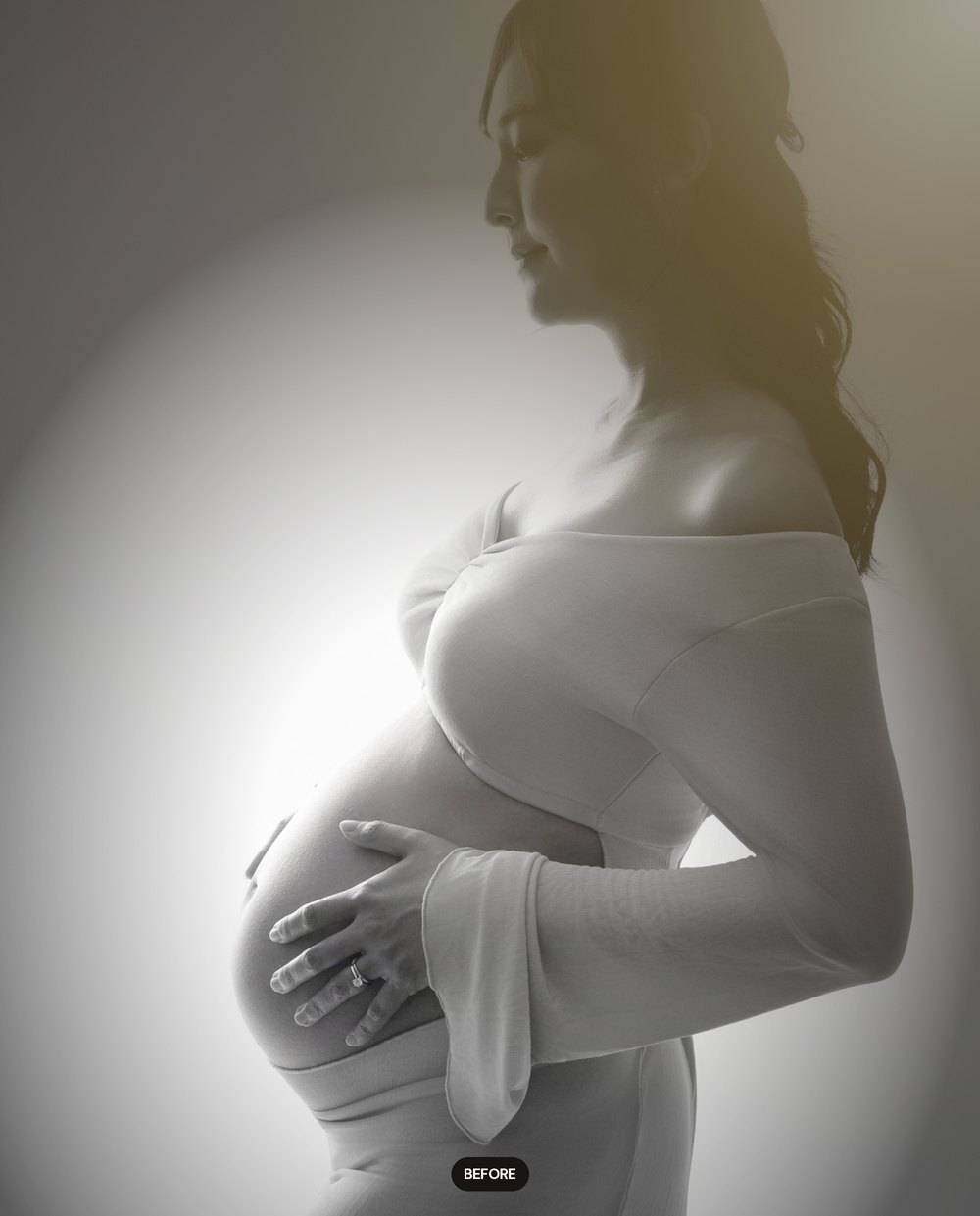 A maternity portrait before the snoot effect, evenly lit against a pale wall